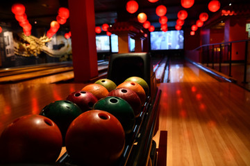 Bowling lane and balls in the row in bowling center.