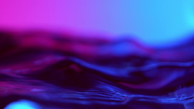 Super slow motion of splashing water wave illuminated by neon lights. Filmed on very high speed camera, 1000 fps.