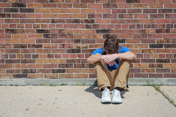 Depressed upset student sitting outside school