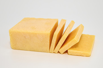 Cheddar cheese brick with slices isolated on white background.
