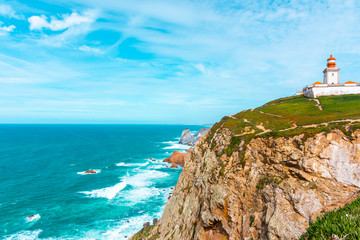The lighthouse on the cliff in Cabo da Roca (Cape Roca) the westernmost  extent of mainland Portugal, continental Europe and the Eurasian land mass. Bright vivid landscape.