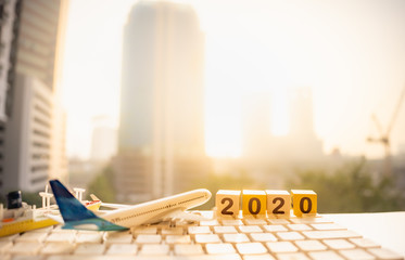 Wooden word number 2020, airplane, ship on white keyboard and blurred city scape and copy space using as background business shipping, rent container, worldwide transportation, new year concept.