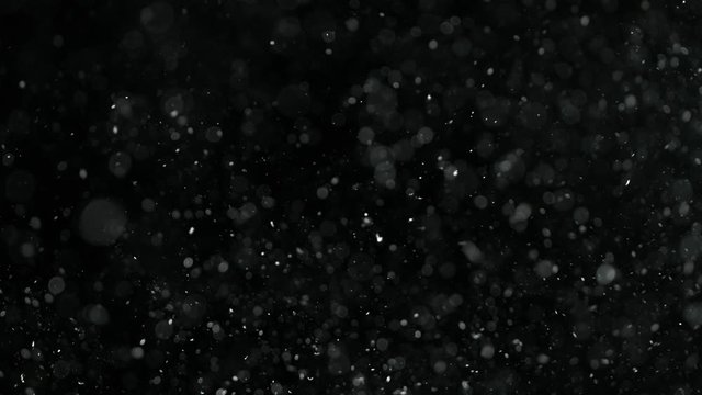 Natural organic dust particles on black background. Glittering Particles With Bokeh. Slow motion at 1000 fps.
