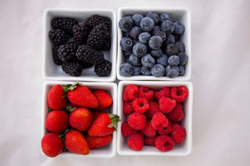 strawberries, blueberries, blackberries and raspberries in the each square bowl