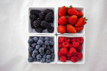 strawberries, blueberries, blackberries and raspberries in the each square bowl