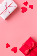 Present to a lover on Valentine's Day. Gift boxes near paper hearts on pink background top-down...