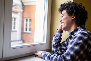 Latin American man looking at a window, cheerful expression 