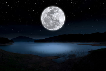 Super full moon over lake in the dark night.