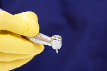 Dentist's hand in glove with dental handpiece.