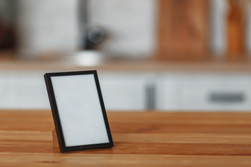 The frame on the wooden table and the blurry interior of the kitchen in the background. Design preparation