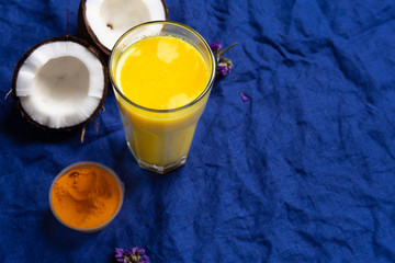 Masala Haldi Doodh. Healthy vegetarian coconut golden milk with turmeric and honey on a classic blue textile background