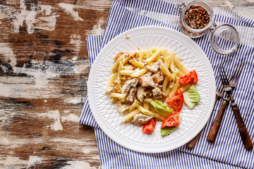 Penne pasta with chicken, smoked cheese and spices on a white plate. Traditional Mediterranean Italian cuisine. Copy space