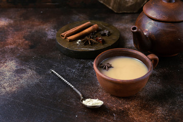 Spicy masala tea in a clay terracotta cup on a dark brown background. Horizontal Image and Copy Space
