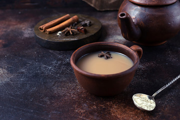 .Spicy masala tea in a clay terracotta cup on a dark brown background. Horizontal Image and Copy Space