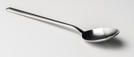 Silver dessert spoon cutlery on grey background