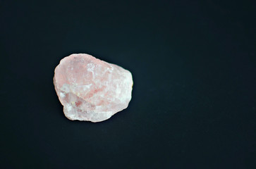 raw rose quartz crystal on black background, copy space