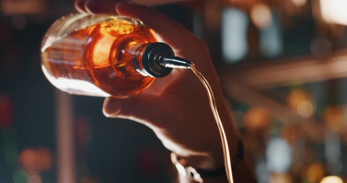 Titolo: Close up of a professional bartender is preparing an alcoholic cocktail with professional crystal long lasting ice cube to customers at the bar or disco club.