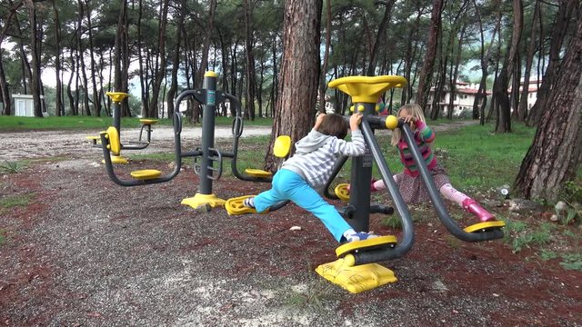 Akyaka, Mugla, Turkey - 10th of November 2019: 4K Sportive children do the splits on fitness machines outdoors