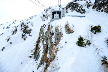 Fototapeta na wymiar Ski Cable car travel destination, Ropeway Alpine Snow Wall Walk or airline cable rope way setting on to of mountain, transportation from and to the peak point of Tateyama Kurobe Alpine Route, Japan. 