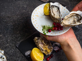 Open oyster in hands, against a background of open oysters, selective focus