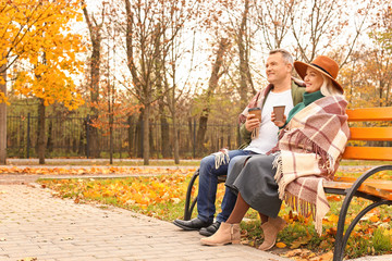 Happy mature couple drinking coffee in autumn park