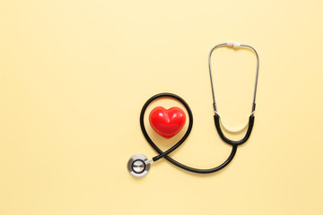 Stethoscope and red heart on color background. Cardiology concept