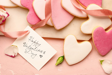 Board with tasty heart-shaped cookies and greeting card on color background. Valentines Day...