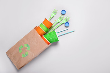 Plastic cups, forks and paper bag on grey background. Recycling concept
