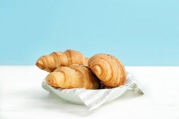 Plate with tasty croissants on white table