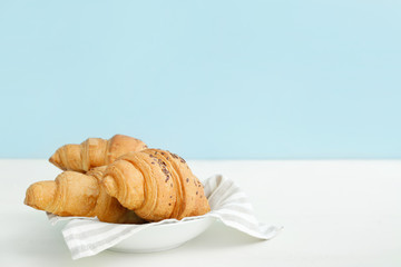 Plate with tasty croissants on white table