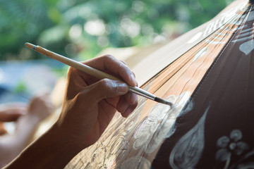 Close-up of young person hand painting on umbrella with Boken background