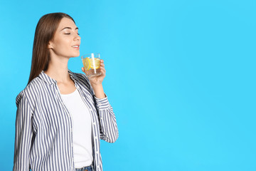 Young woman with glass of lemon water on light blue background. Space for text