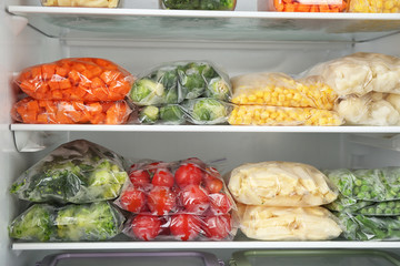 Plastic bags with different frozen vegetables in refrigerator