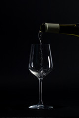 pouring wine into empty glass black background