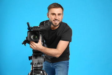 Operator with professional video camera on blue background