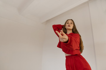 Cute teen girl actively dancing in a red suit.