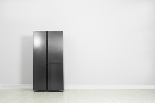 Modern Refrigerator Near Light Grey Wall, Space For Text