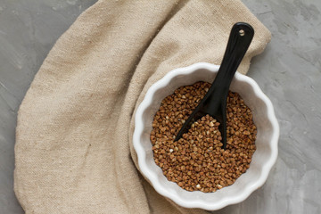 Buckwheat in A white dish on a wooden gray table. The view from the top. Space for text. delicious and healthy food and nutrition. vitamins for humans. cereals and grains.