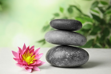 Fototapeta na wymiar Zen lifestyle. Beautiful lotus flower and stones on white wooden table