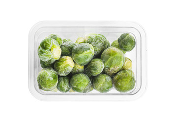 Frozen Brussels sprouts in plastic container isolated on white, top view. Vegetable preservation