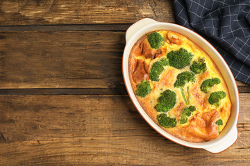 Tasty broccoli casserole in baking dish on wooden table, top view. Space for text