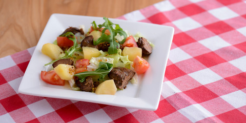 Healthy mix breakfast lunch dinner on a plate, potatoes, grilled meat, tomatoes, salad, sauce in cafe, restaurant.