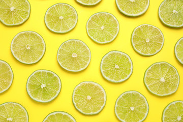 Fototapeta premium Fresh juicy lime slices on yellow background, flat lay