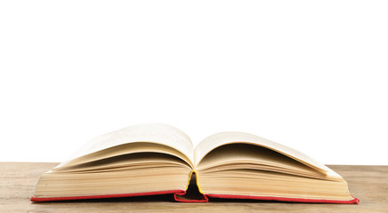 Open book on wooden table against white background