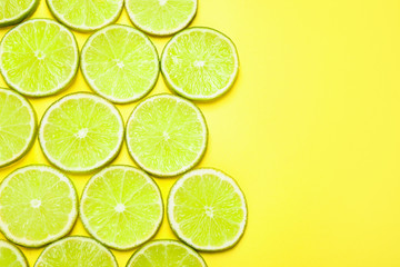 Fototapeta na wymiar Juicy fresh lime slices on yellow background, flat lay. Space for text