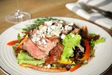 Delicious salad with roasted meat and vegetables served on table, closeup