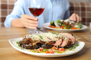 Delicious roasted meat and blurred woman on background