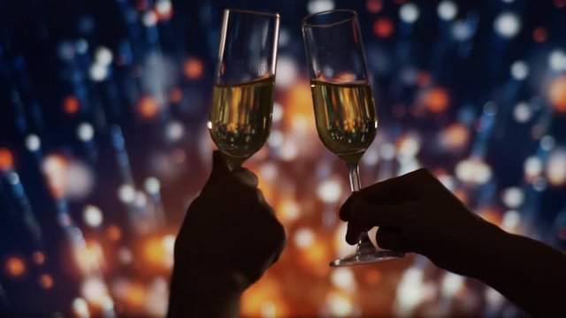 Hands Clinking with Two Glasses of Champagne with bubbles over fireworks Bokeh