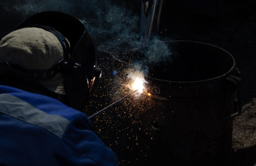 An experienced welder at work. Preparation and welding process of cast iron furnace. Selection focus. Shallow depth of field