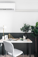 Stylish working corner in scandinavian style with nice decoration and artificial plant in natural light setting scene / interior design / stylish decor / wall type air conditioning